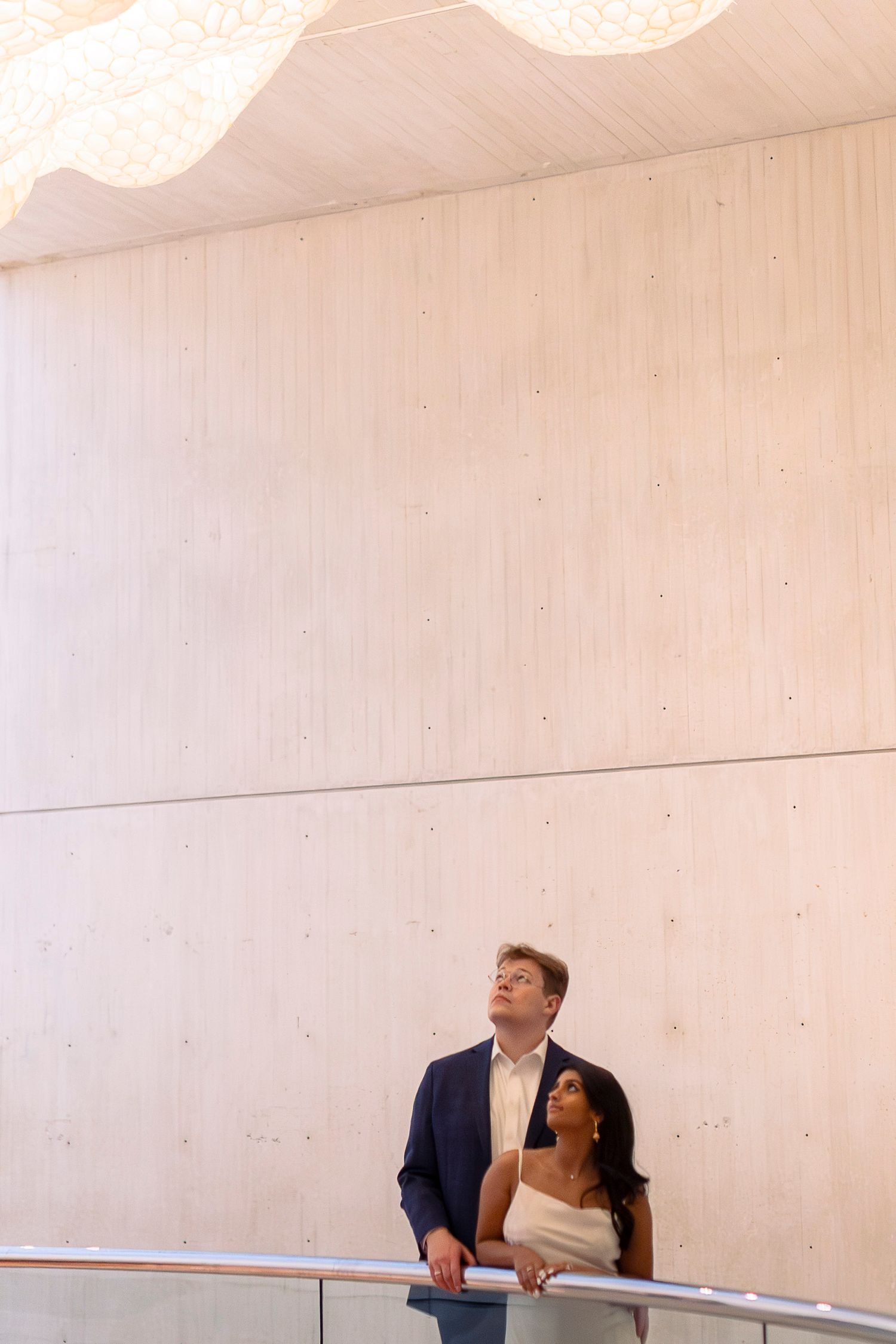 Two people laugh and smile together while sitting at a table in a minimalist white room.