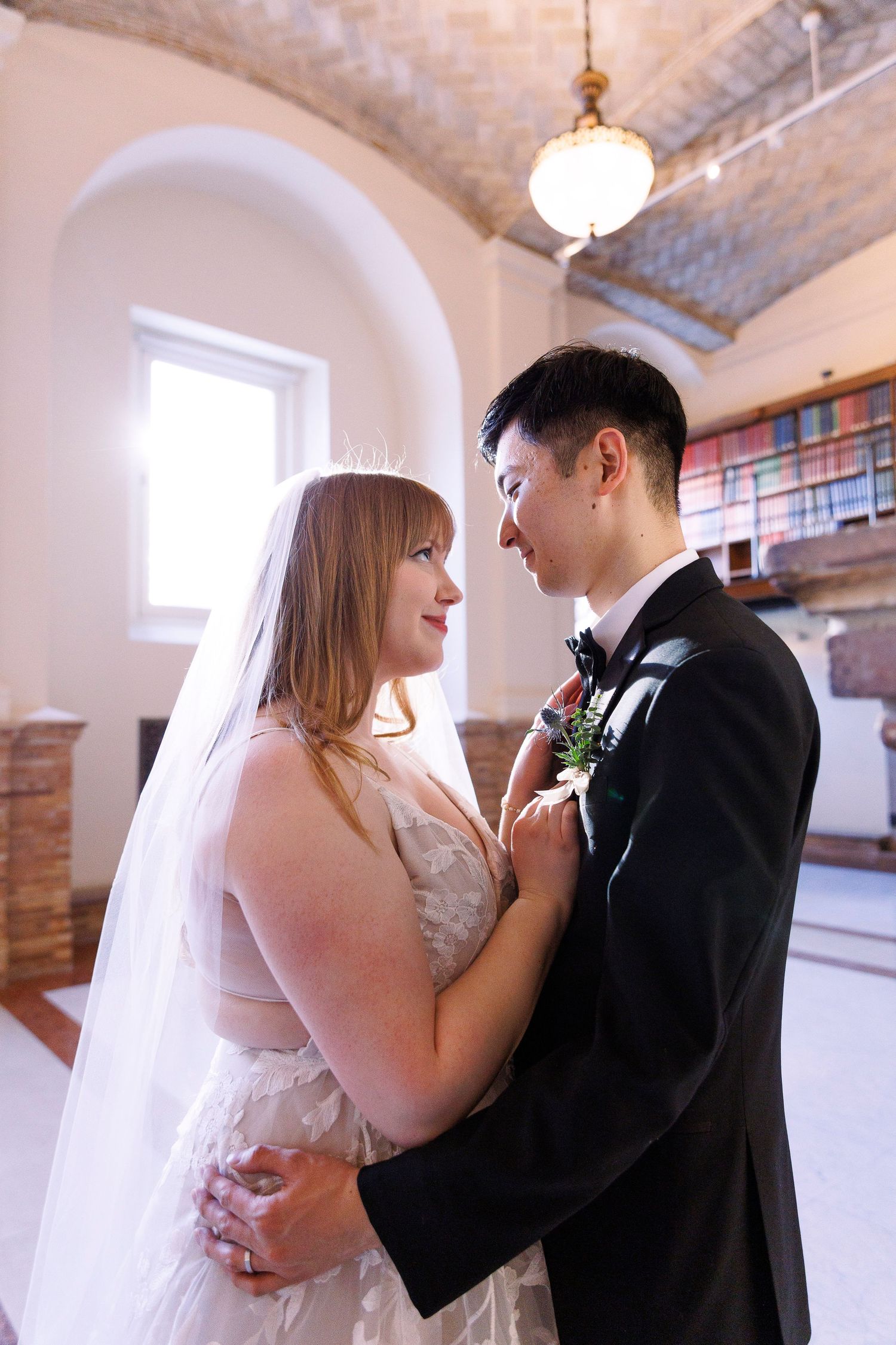 A bride and groom share a romantic moment during their first dance in an elegant indoor venue with exposed brick walls.