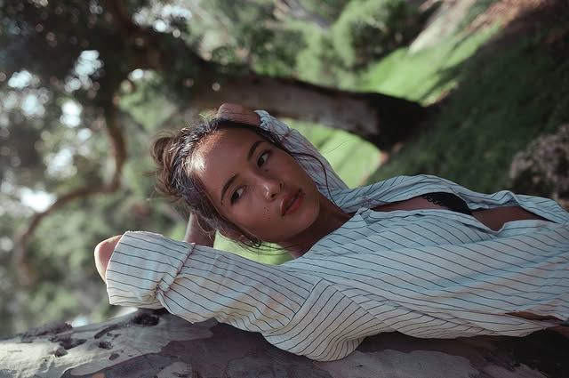 A figure reclines peacefully among greenery and natural surroundings.