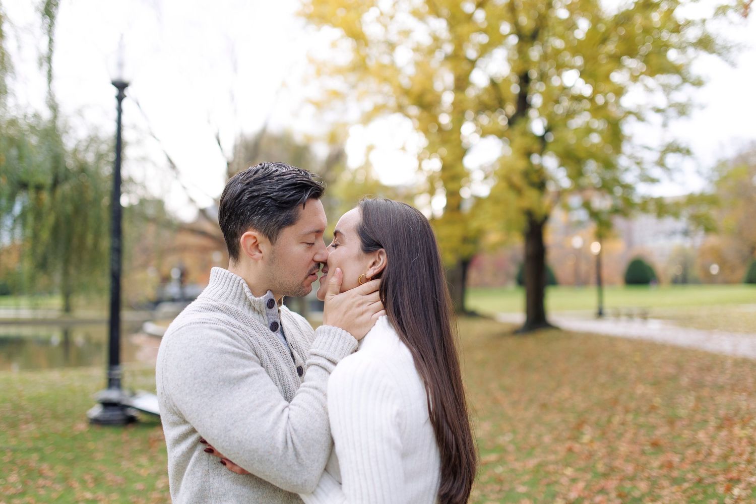Romantic couple shares tender moments in a park with autumn leaves falling around them in multiple candid shots.
