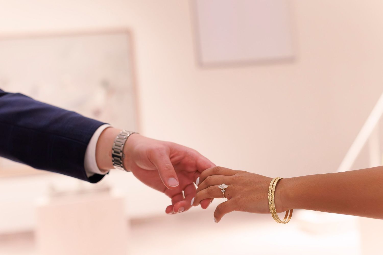 Close-up of hands exchanging wedding rings during a ceremony against a soft blurred background.