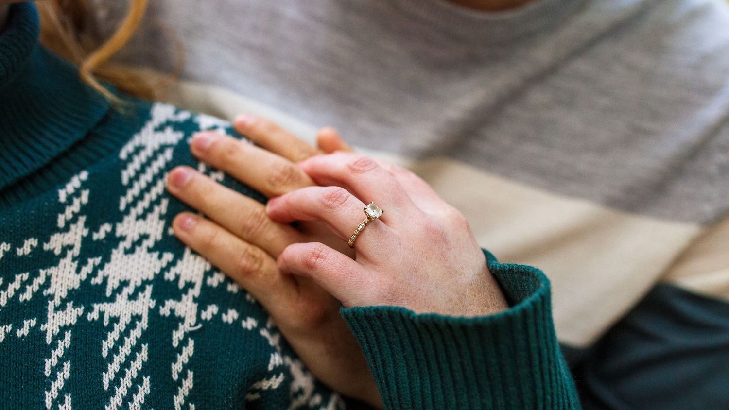 A pair of hands hold a warm cup of coffee in a cozy green sweater setting.