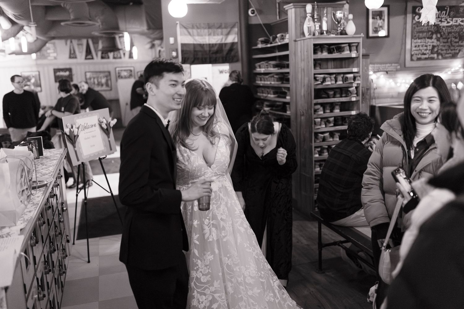A joyful celebration takes place in a cozy restaurant with a bride in white surrounded by guests at a wedding reception at Flatbreads.