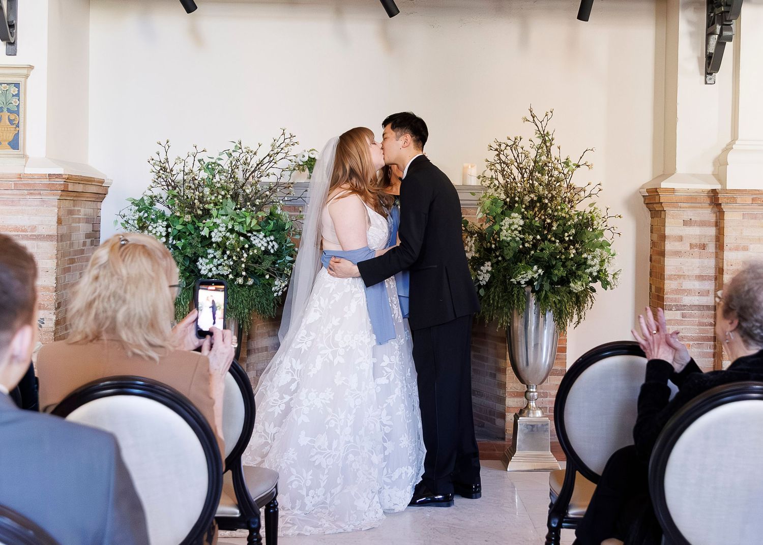 Wedding photographer captures candid moments of a bride and groom during their outdoor photo session at a venue.