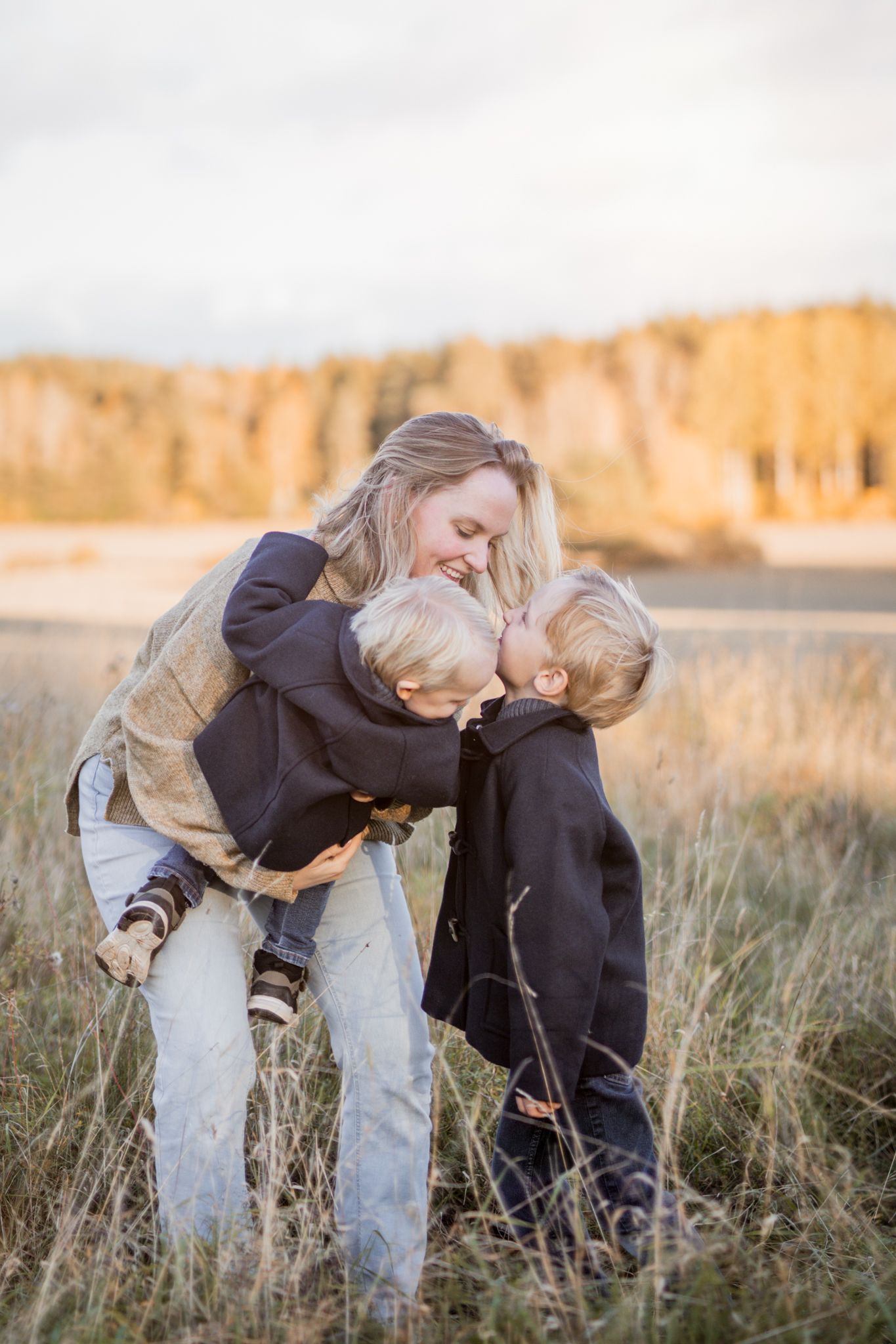 A tender moment captured in a sunlit field of tall grass during golden hour.