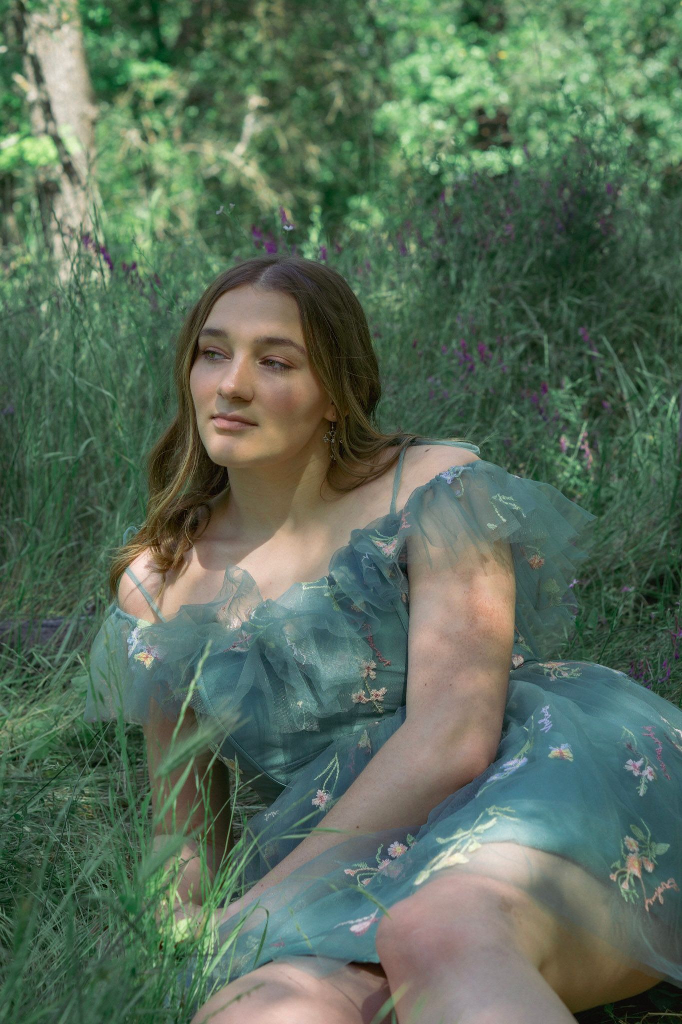 Ethereal outdoor portrait in floral dress among lush green foliage.