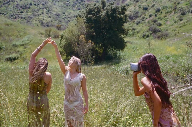 People walking through a sunlit meadow on a grassy hillside.