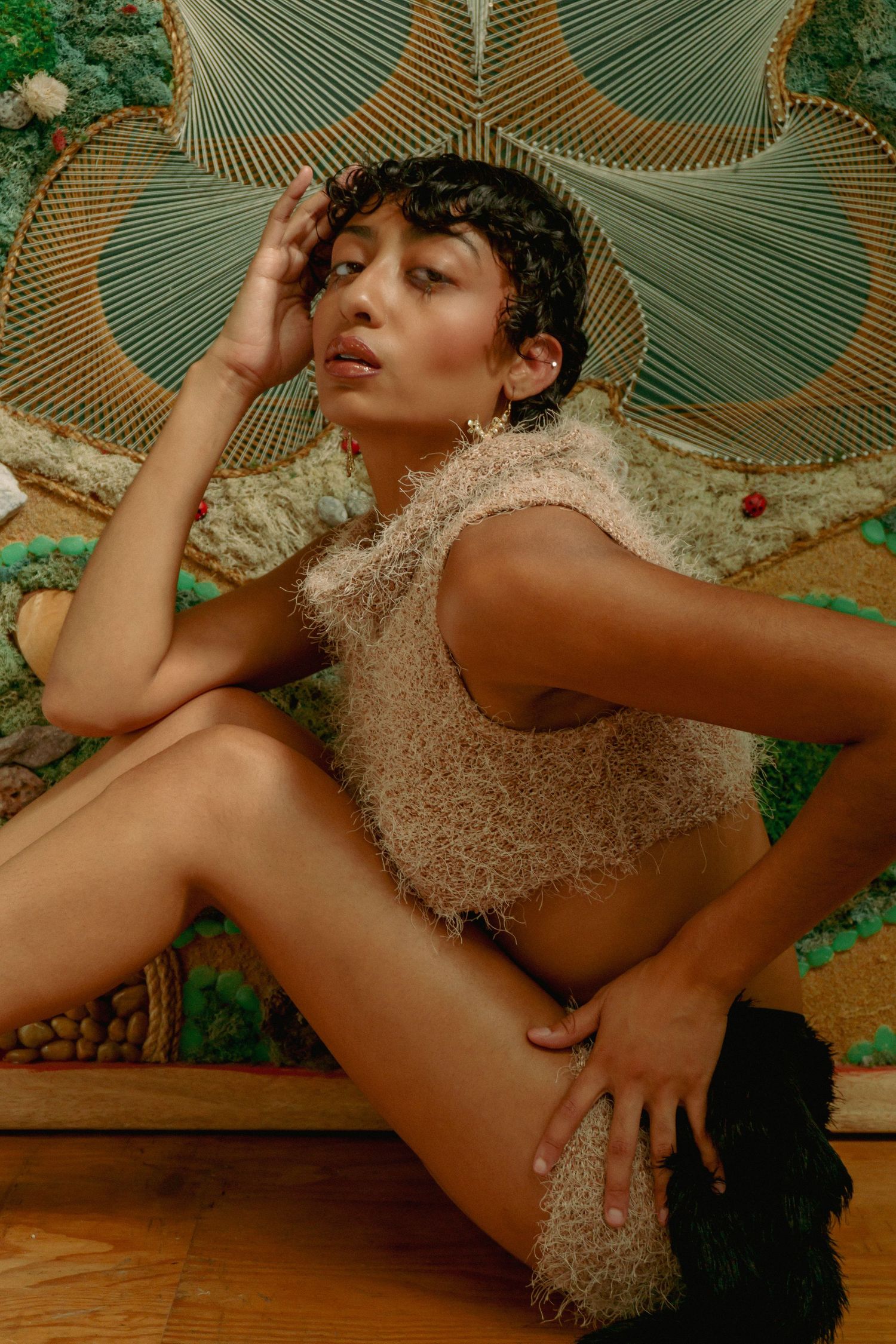 Fashion photography with vintage-inspired styling against detailed mosaic wall art.