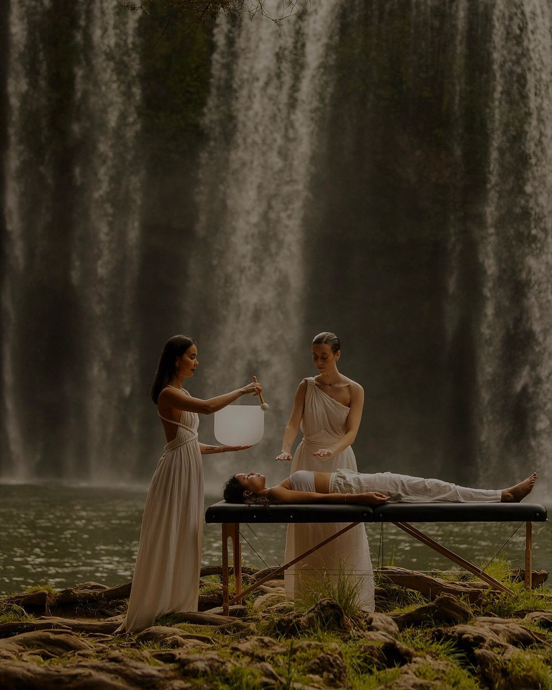Ethereal waterfall scene with figures in white dresses creating a mystical atmosphere.