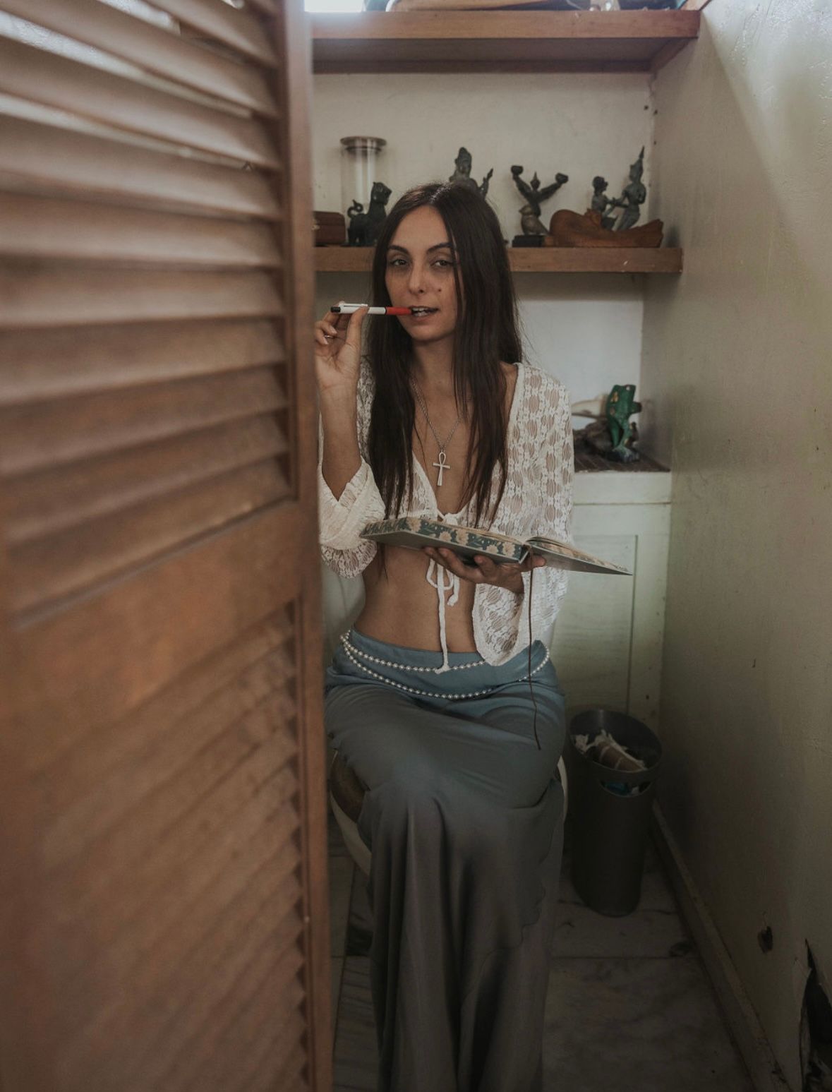 Indoor portrait with lace top and flowing skirt among potted cacti on wooden shelves.
