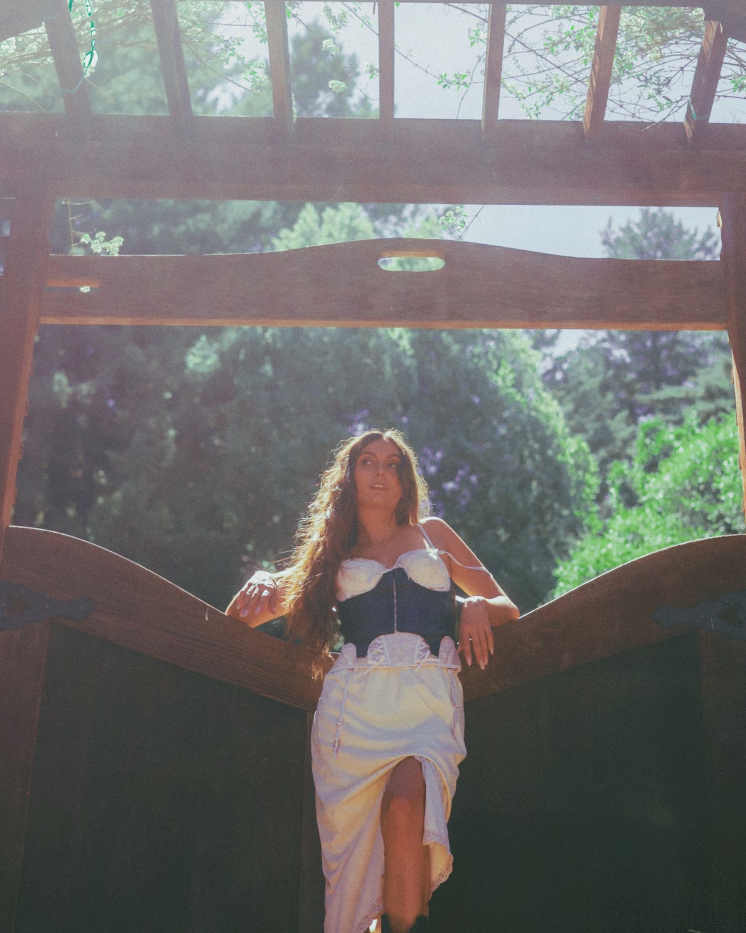 Sunlit portraits under wooden pergola with natural lighting effects.