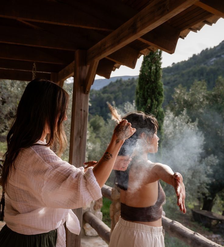 Atmospheric sequence of people releasing smoke or incense in an outdoor covered space.
