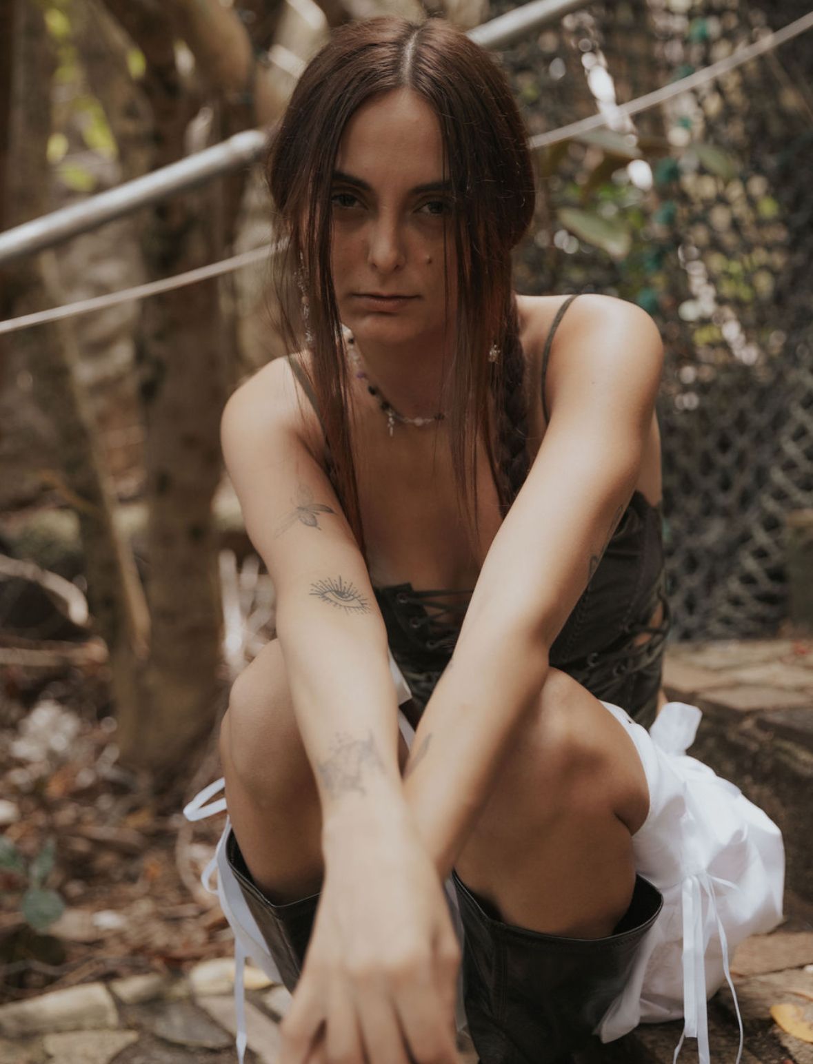 Moody outdoor portrait with dark clothing and wet hair in natural setting.