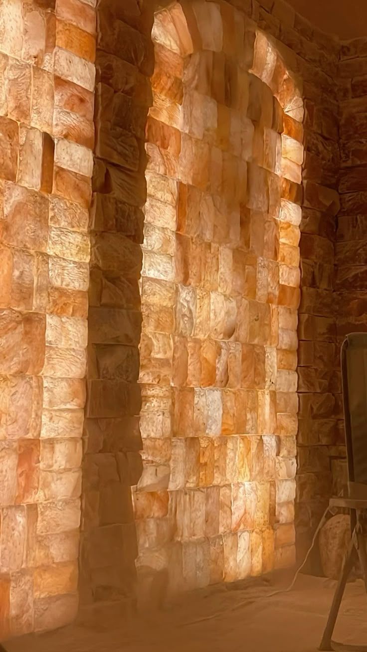 Glowing Himalayan pink salt brick wall with arched alcove, illuminated from behind in warm orange tones.