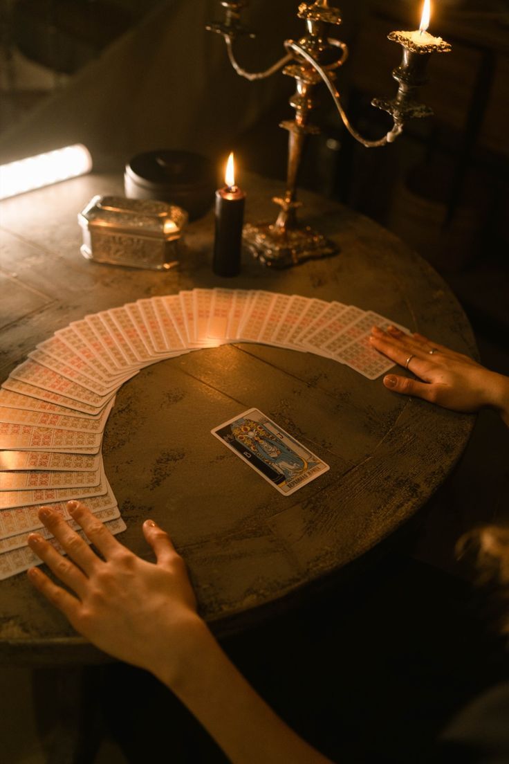 Candlelit tarot reading scene with cards spread out on a dark wooden table.
