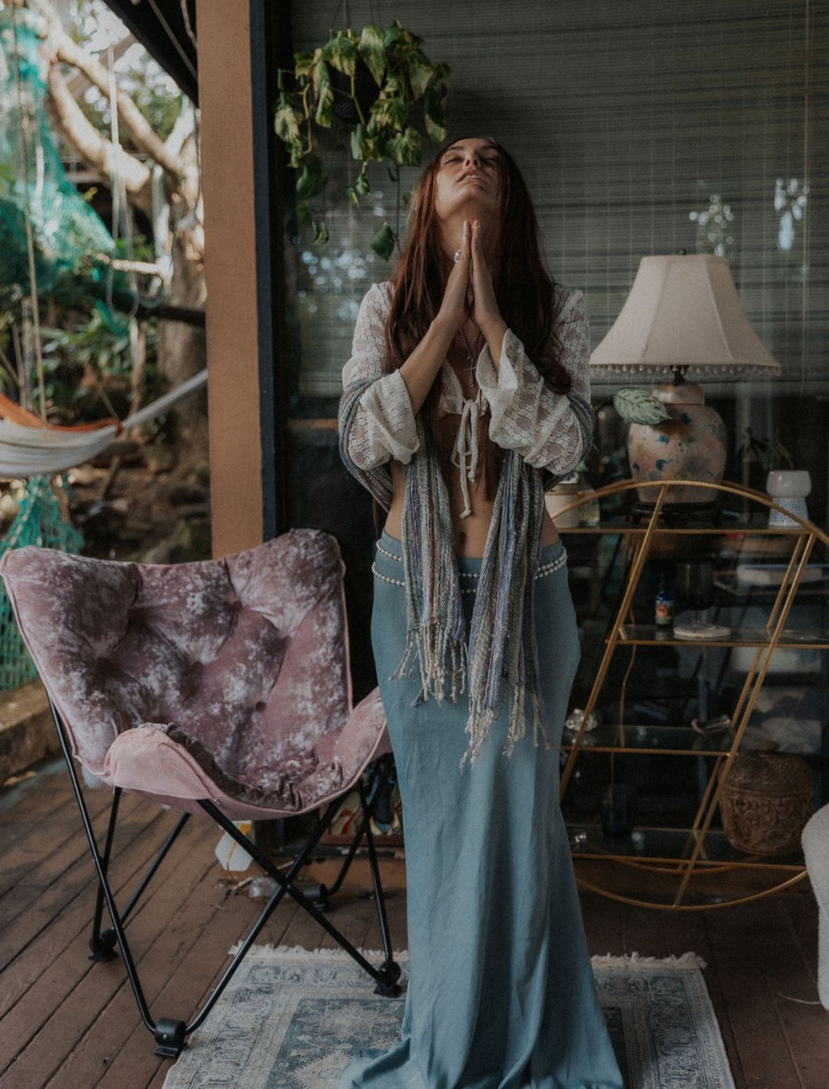 Bohemian style portrait on porch with flowing dress and butterfly chair in background.