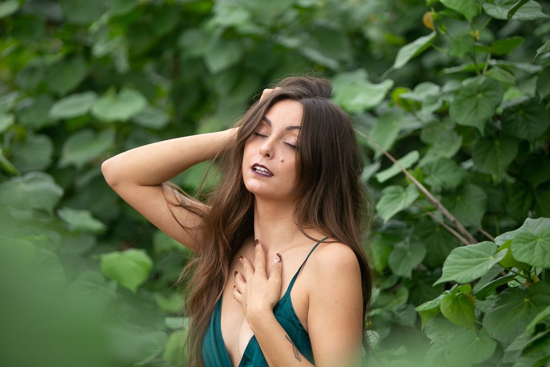 Romantic portrait in green foliage with natural lighting and emerald dress.