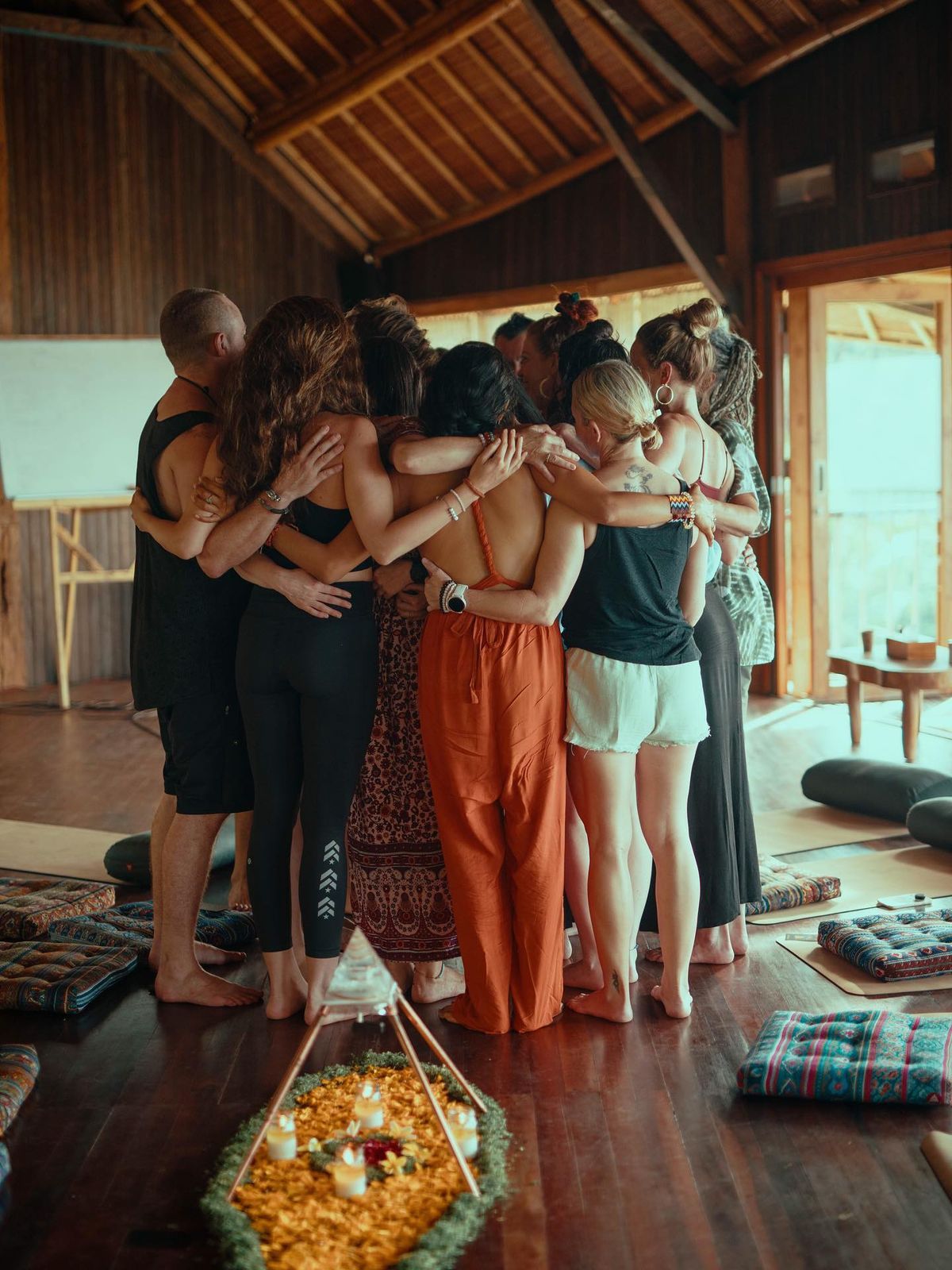 A group forms a circle in a wooden pavilion during what appears to be a wellness retreat.