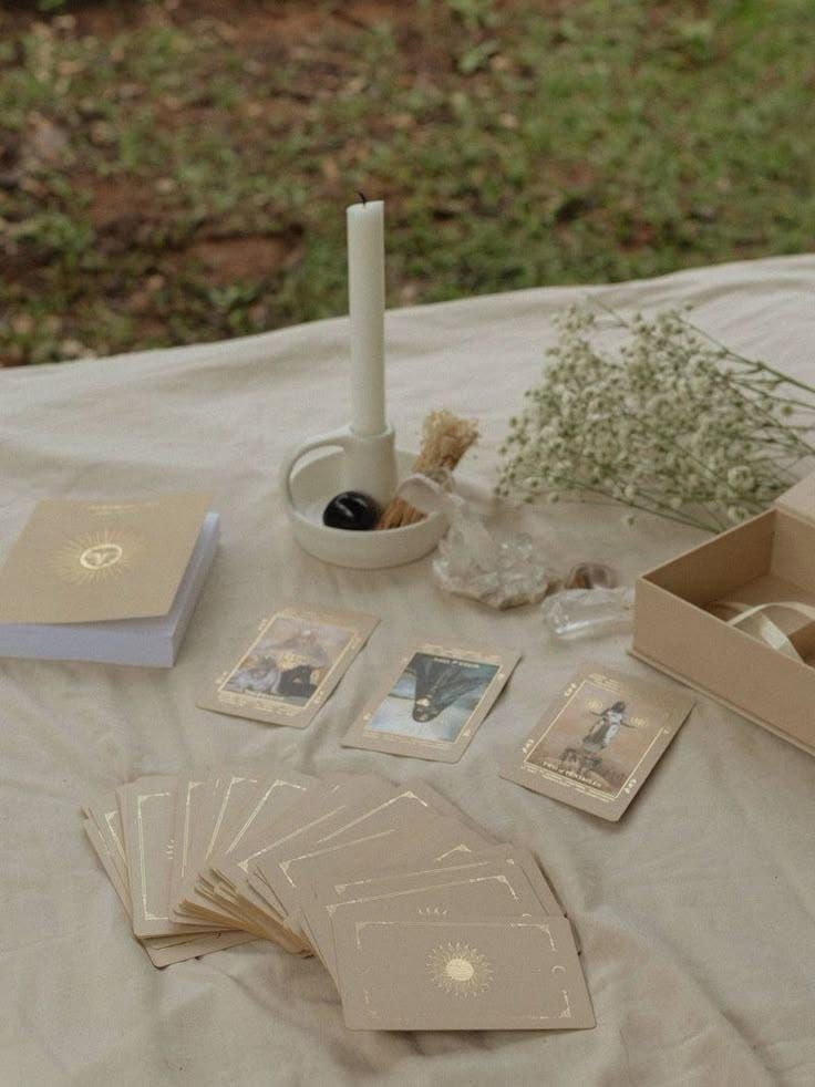 Tarot cards and spiritual items arranged on a light colored tablecloth.