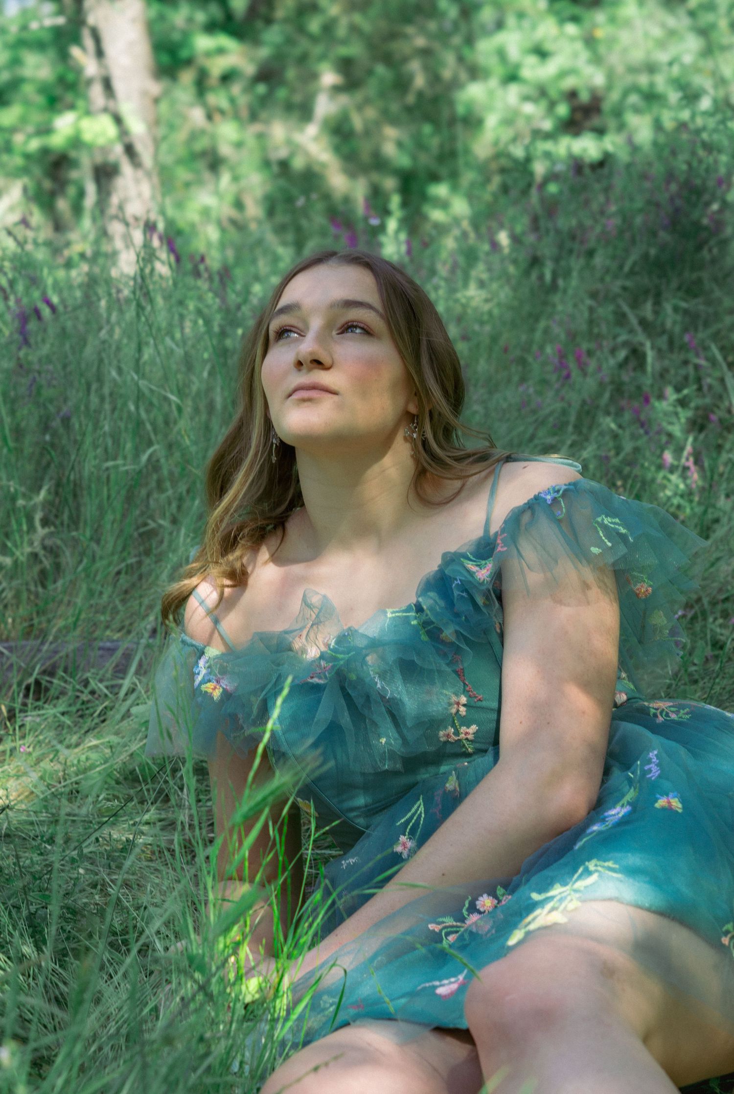 A dreamy summer scene with someone in turquoise reclining in tall grass and wildflowers.