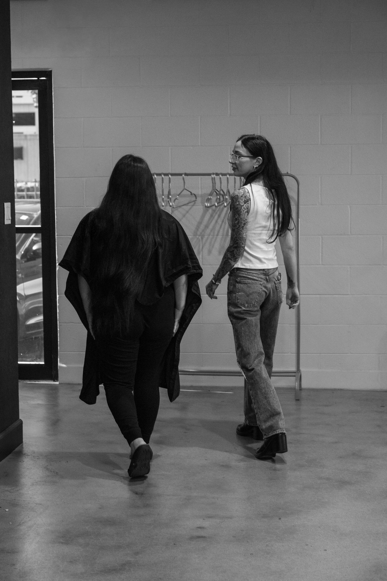 Black and white photo of people walking through industrial hallway.