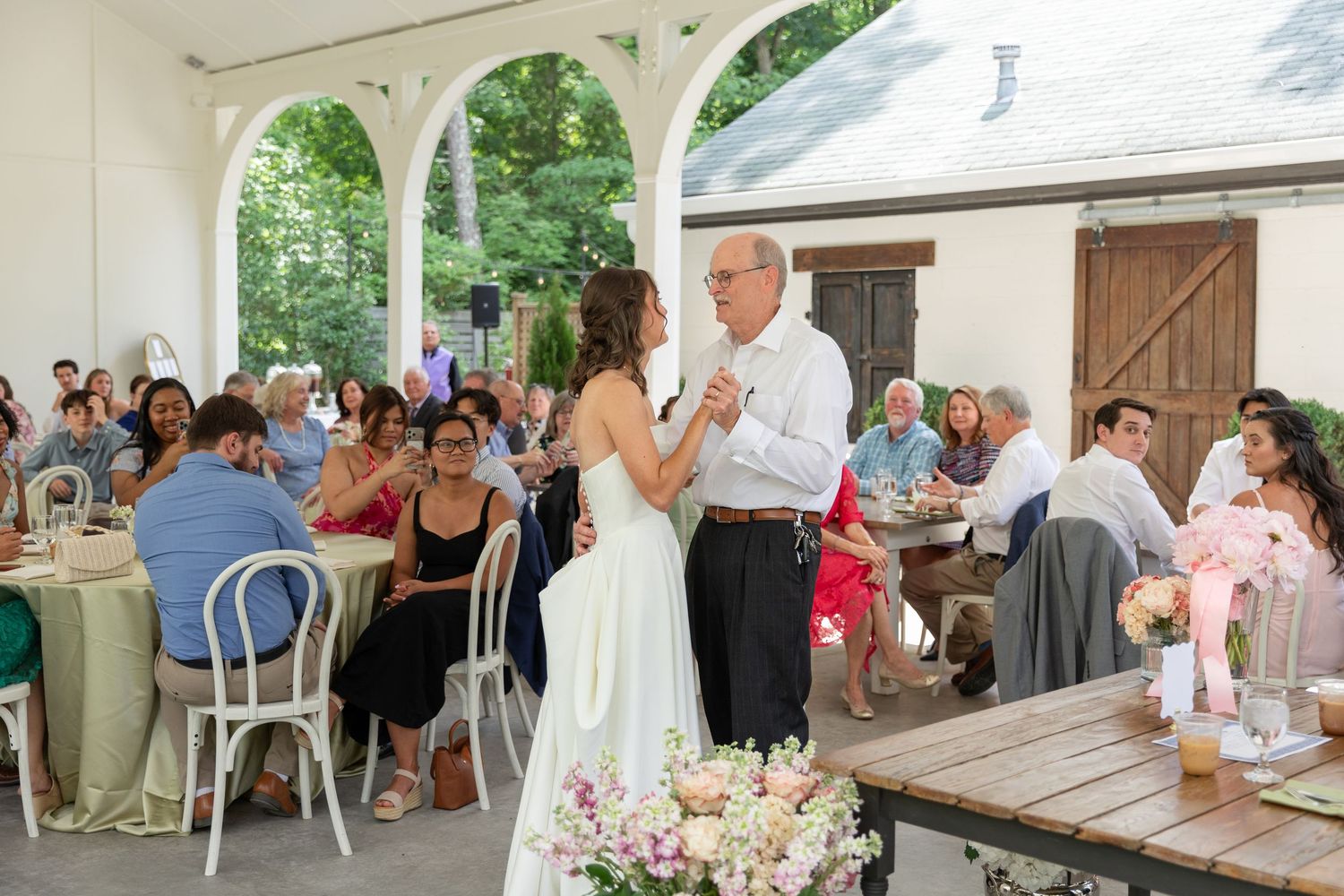 Bride and older gentleman share a father-daughter dance at an elegant outdoor tented wedding reception.