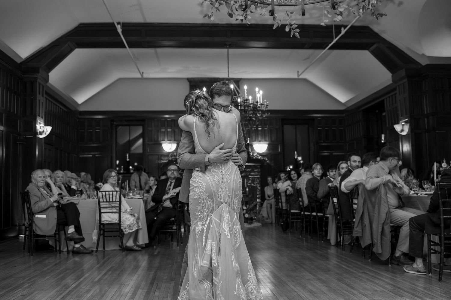 Bride and groom share romantic first dance in black and white photo at elegant wedding reception.