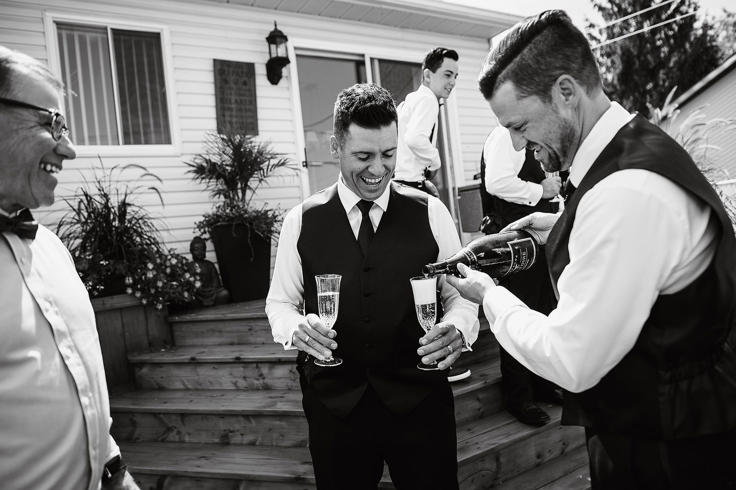 Black and white photo of men in vests gathered on outdoor steps, one holding a guitar.