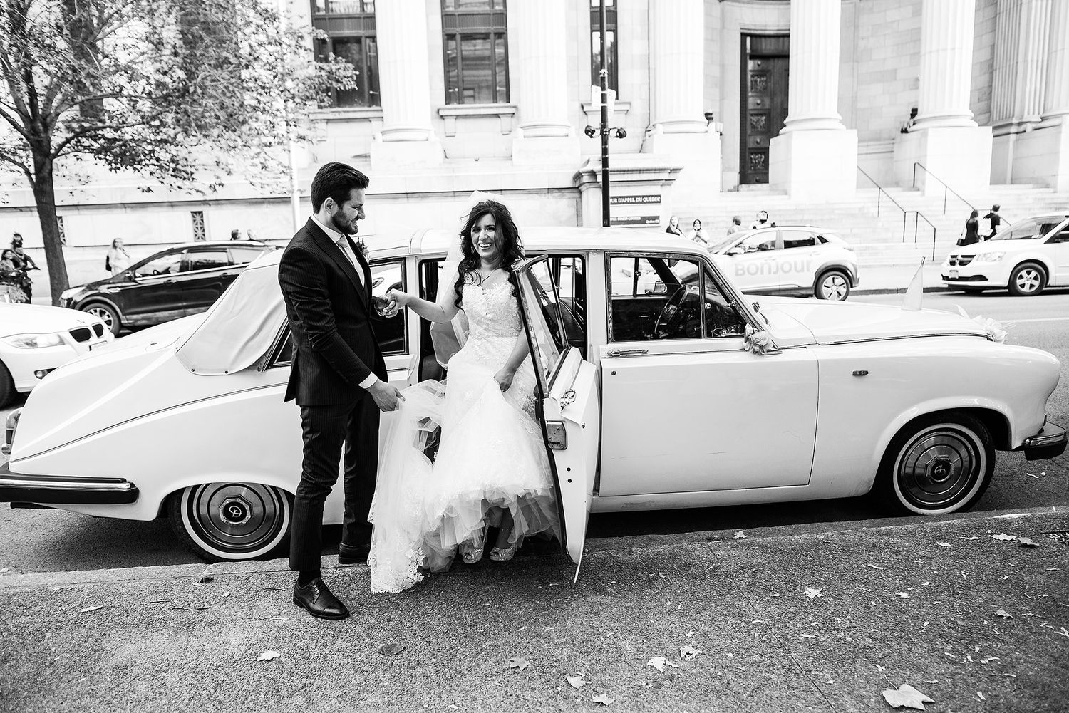 A classic vintage car parked outside a building serves as an elegant wedding day transportation.