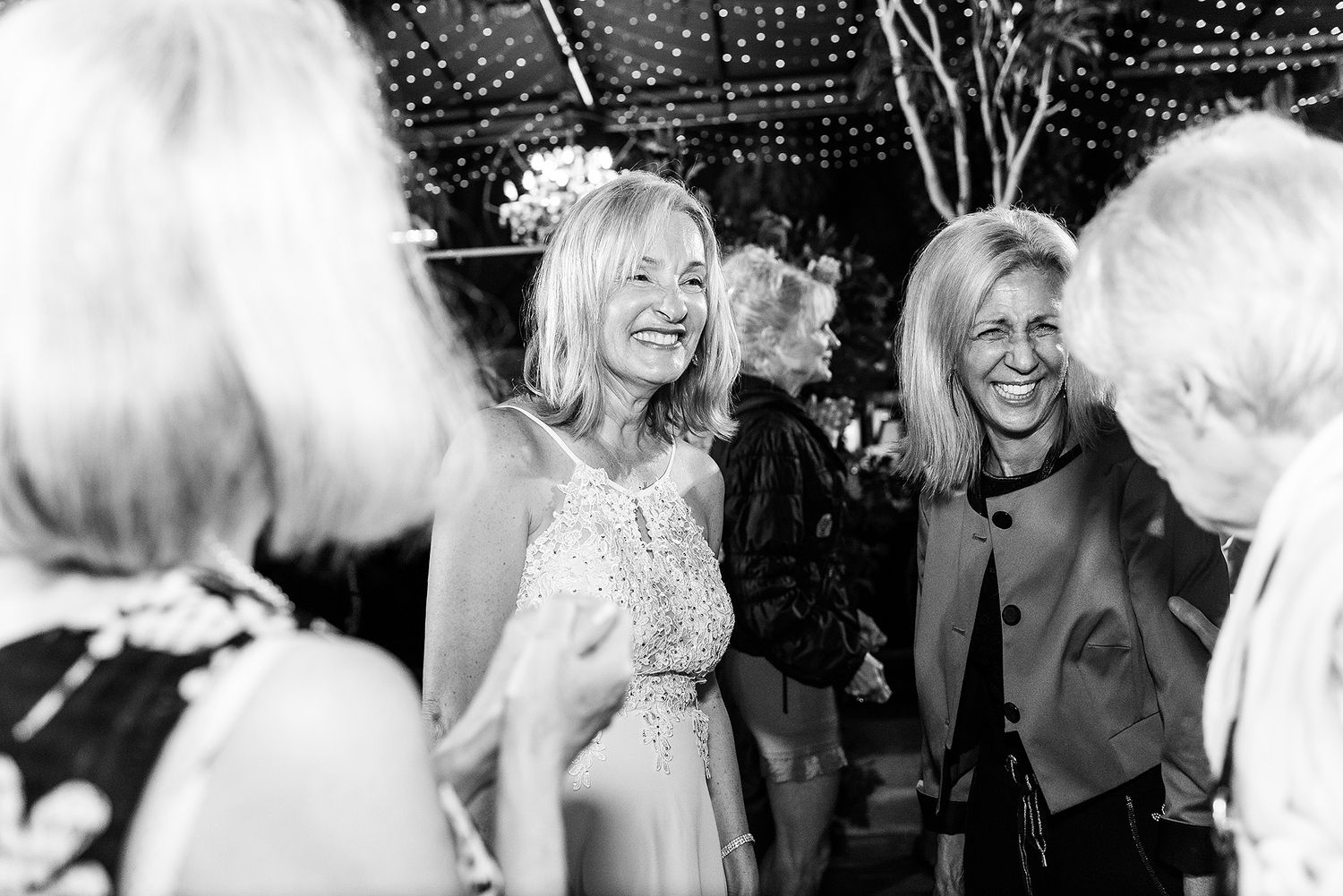 A group of people dancing and celebrating at a party with twinkling lights in the background.