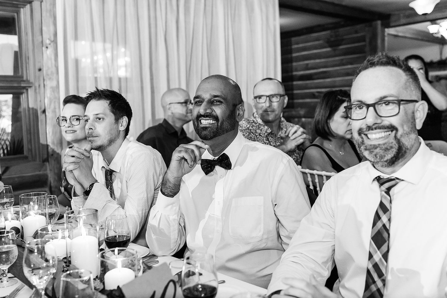 A group of people in white shirts and business attire gather around a table in a social setting.