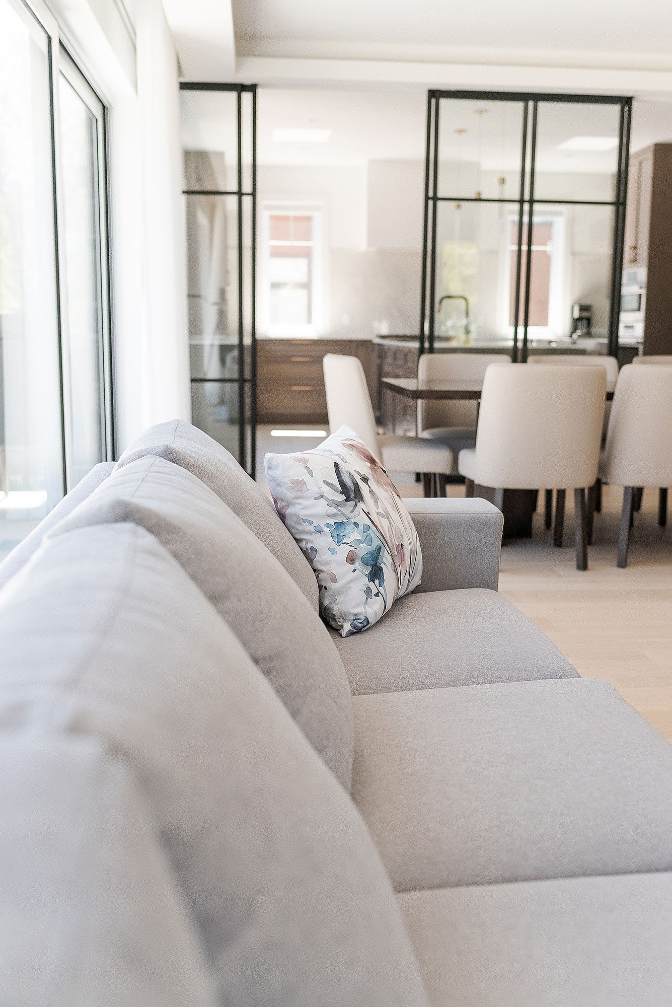Close-up view of a modern gray sectional sofa with decorative throw pillows in a bright contemporary living space.