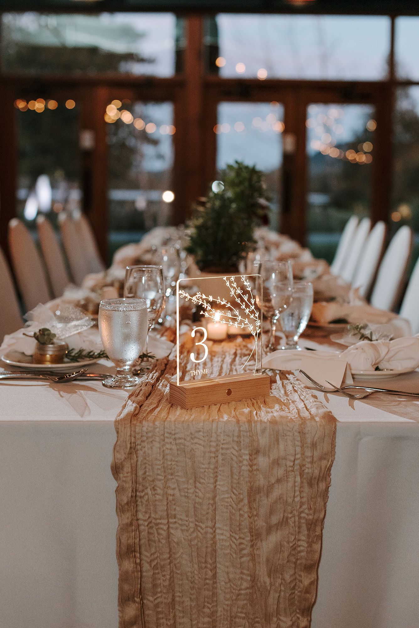 Elegant wedding table setting with white linens, gold runner, and romantic candlelight creating a dreamy atmosphere.