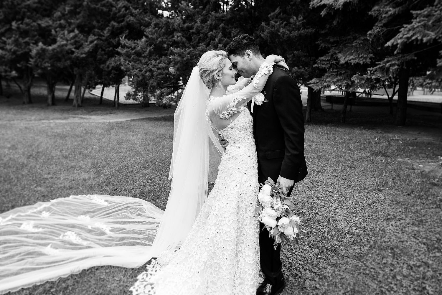 A wedding couple shares a romantic dance outdoors in a garden setting with beautiful natural lighting.