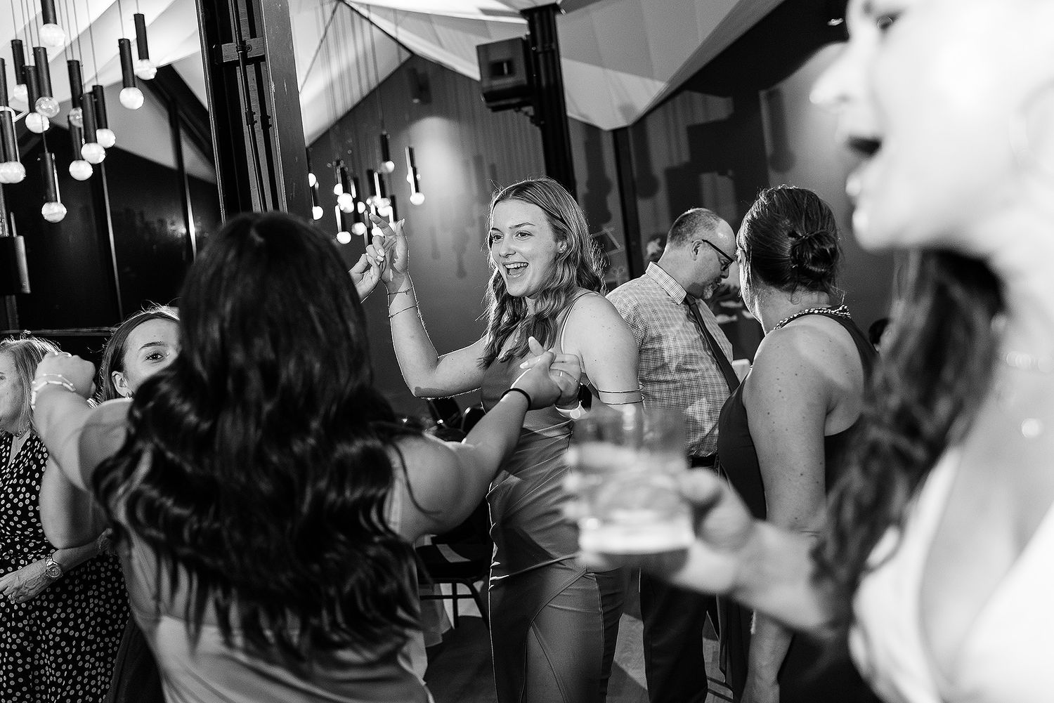 People dancing and celebrating at a lively party or wedding reception with festive decorations and lights.