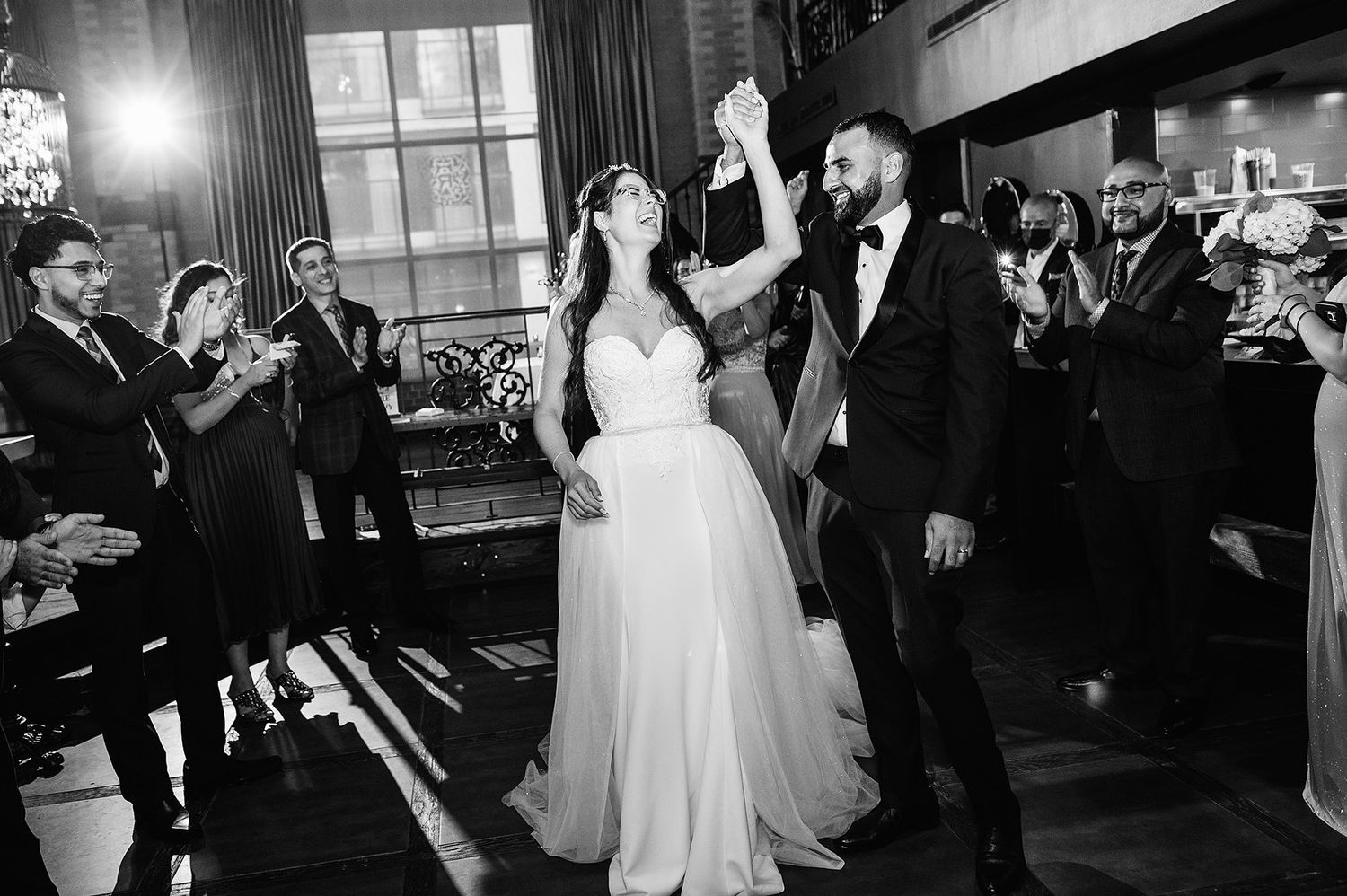 Black and white photo of wedding reception dancing and celebration in an elegant indoor venue.