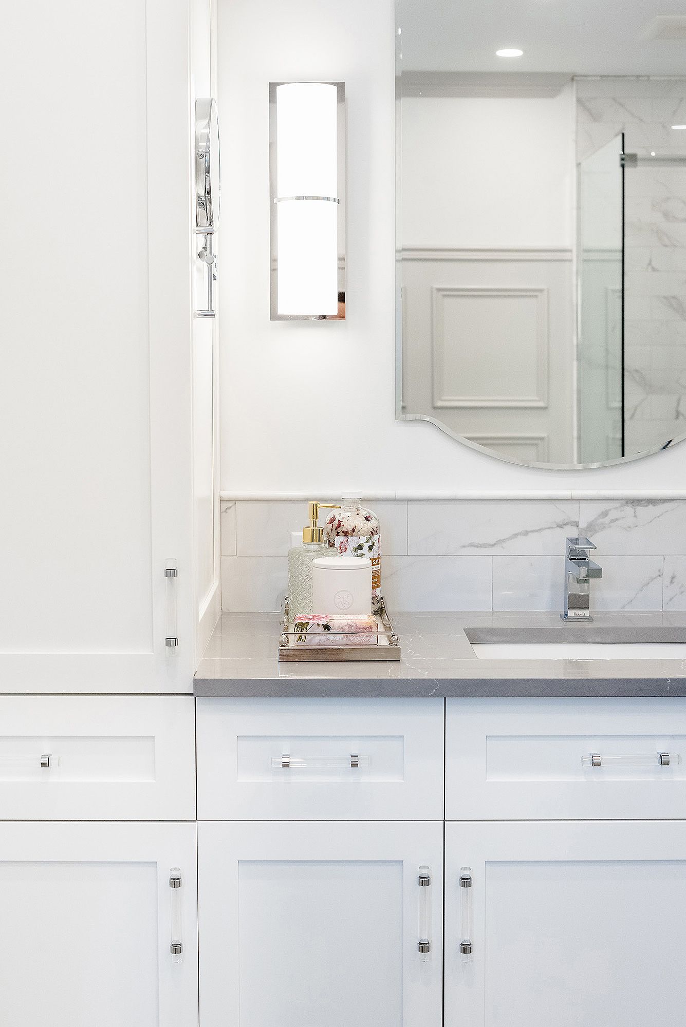 Modern white bathroom vanity with marble countertop, round mirror, and sleek chrome fixtures in a minimalist design.