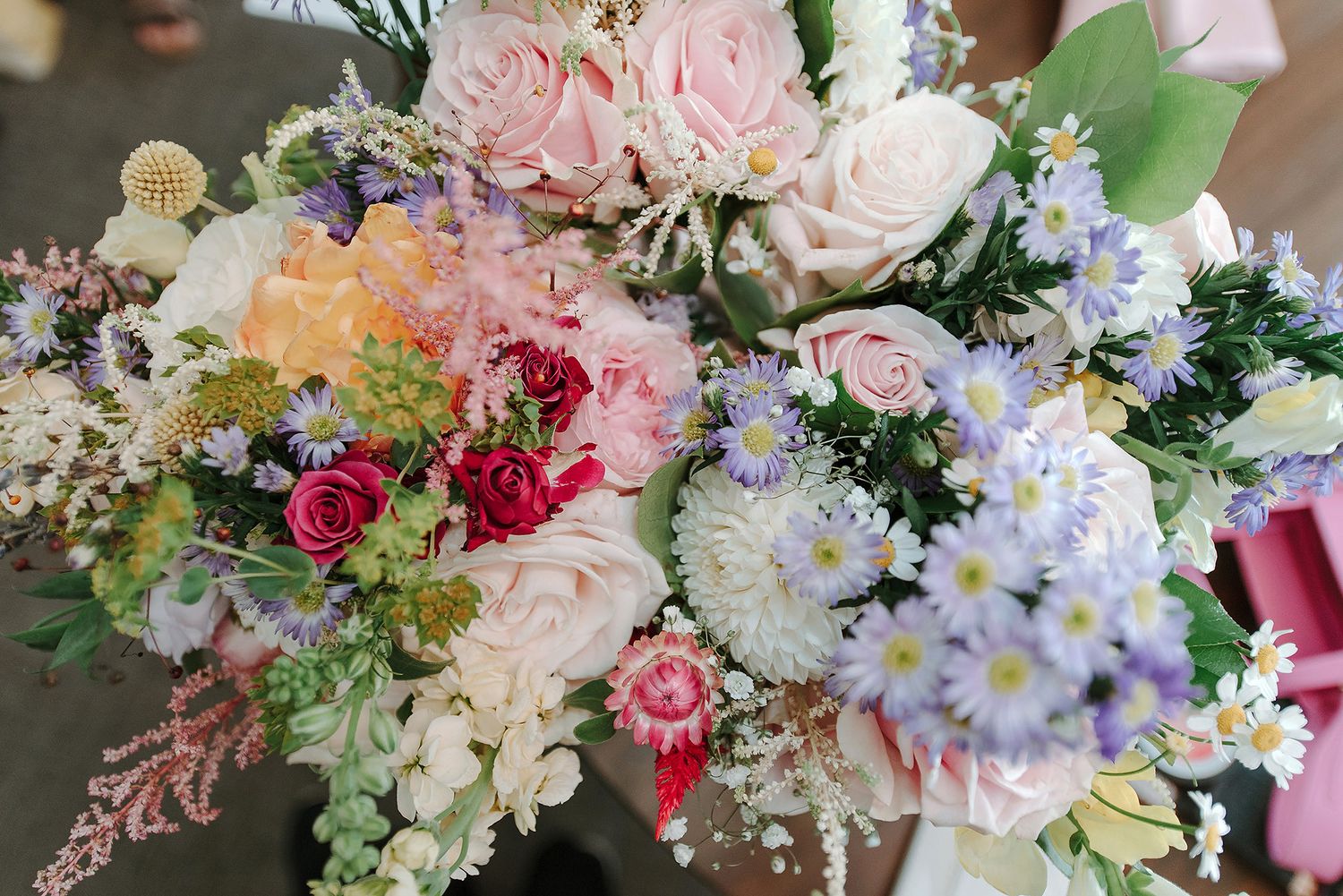 Elegant floral arrangements featuring pink roses, white daisies and mixed blooms in pastel colors for a wedding.