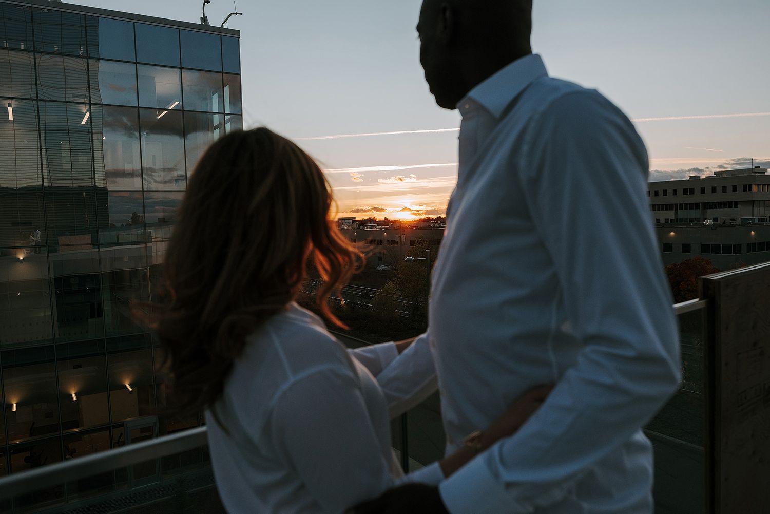 A silhouetted couple sharing an intimate moment at sunset on a rooftop.