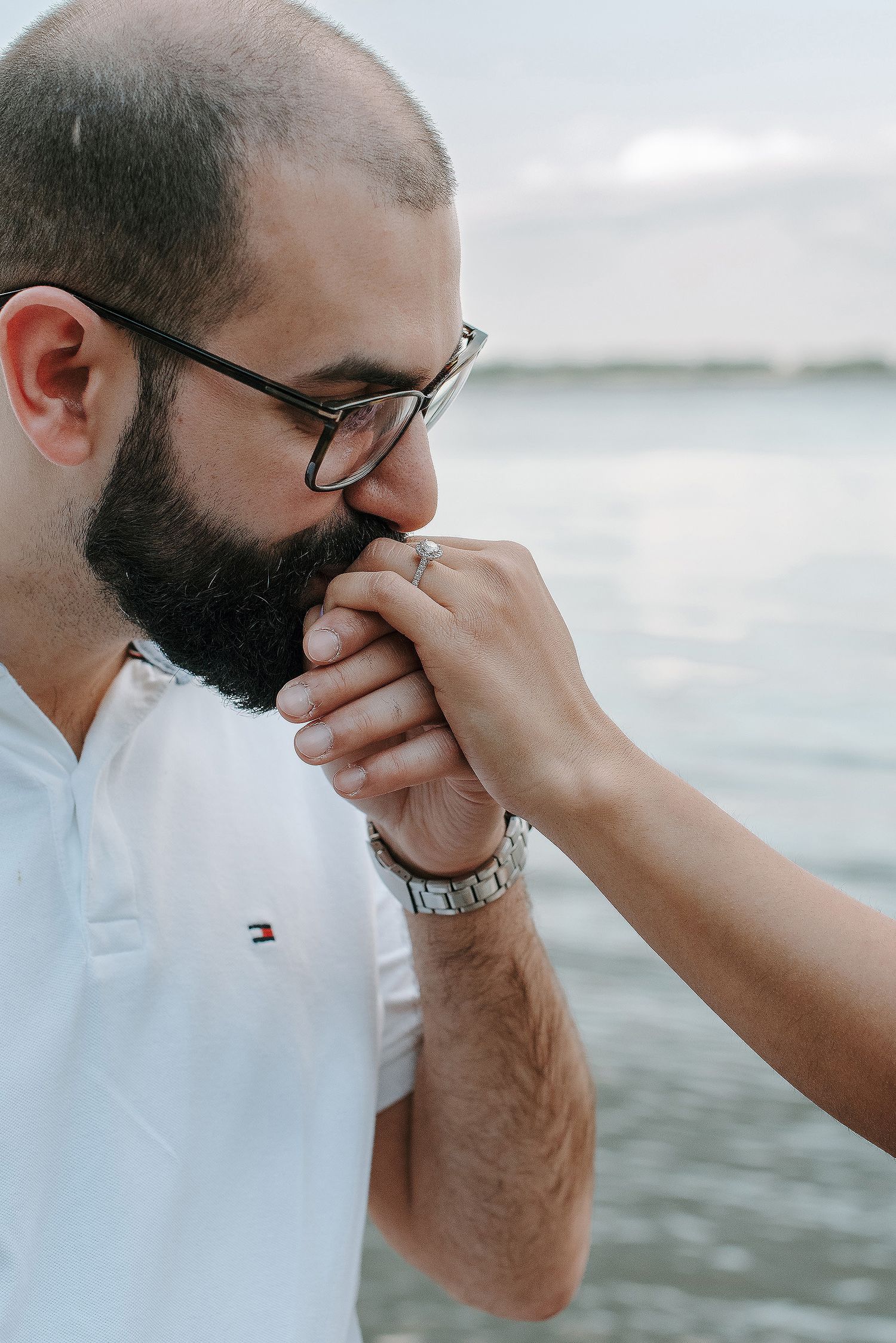 A series of photos showing someone in a white shirt and glasses wiping their face near the ocean.