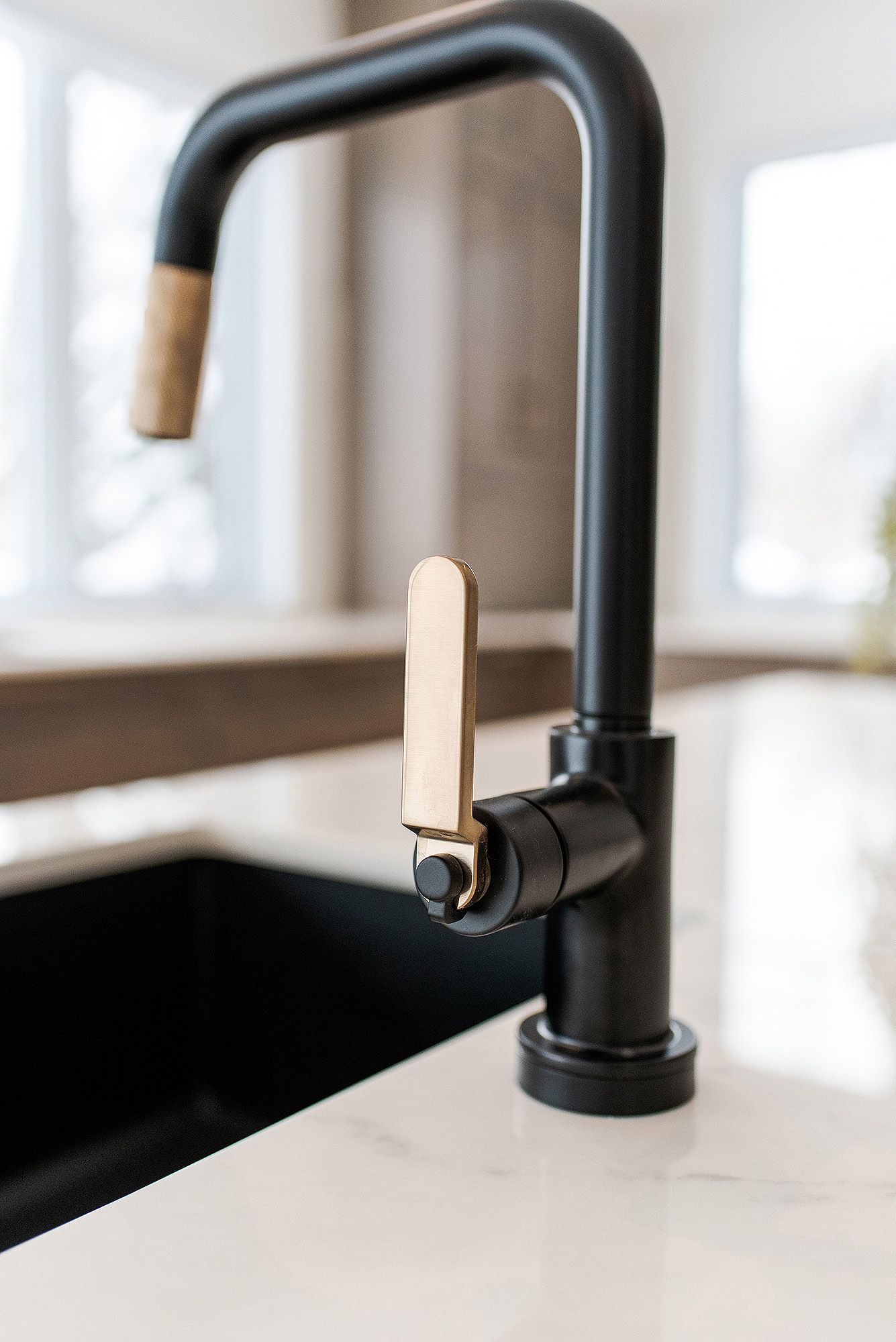 Modern black kitchen faucet with wooden accent details mounted on white countertop.