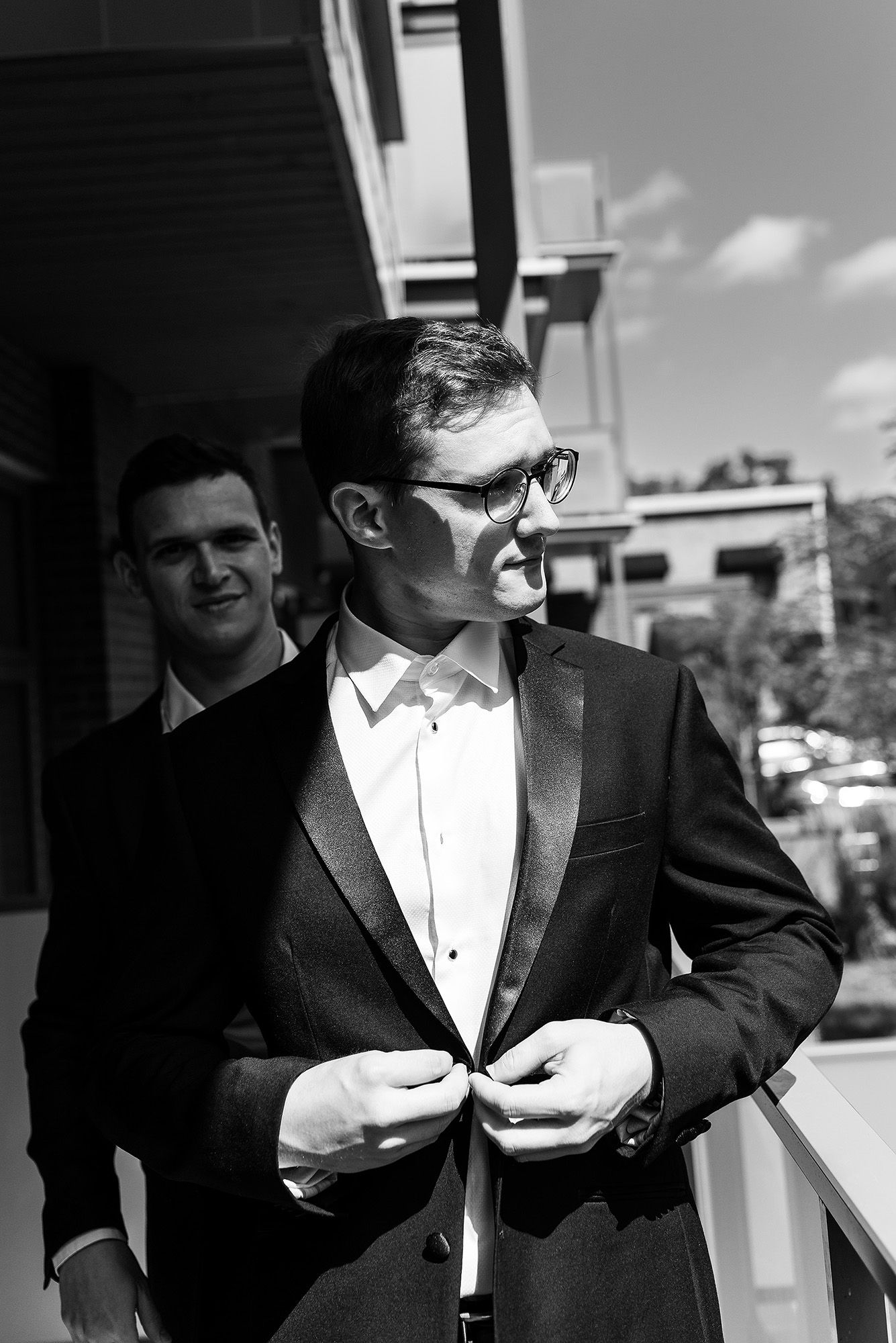 Groomsmen in black tuxedos and white shirts laughing together at a formal wedding event.