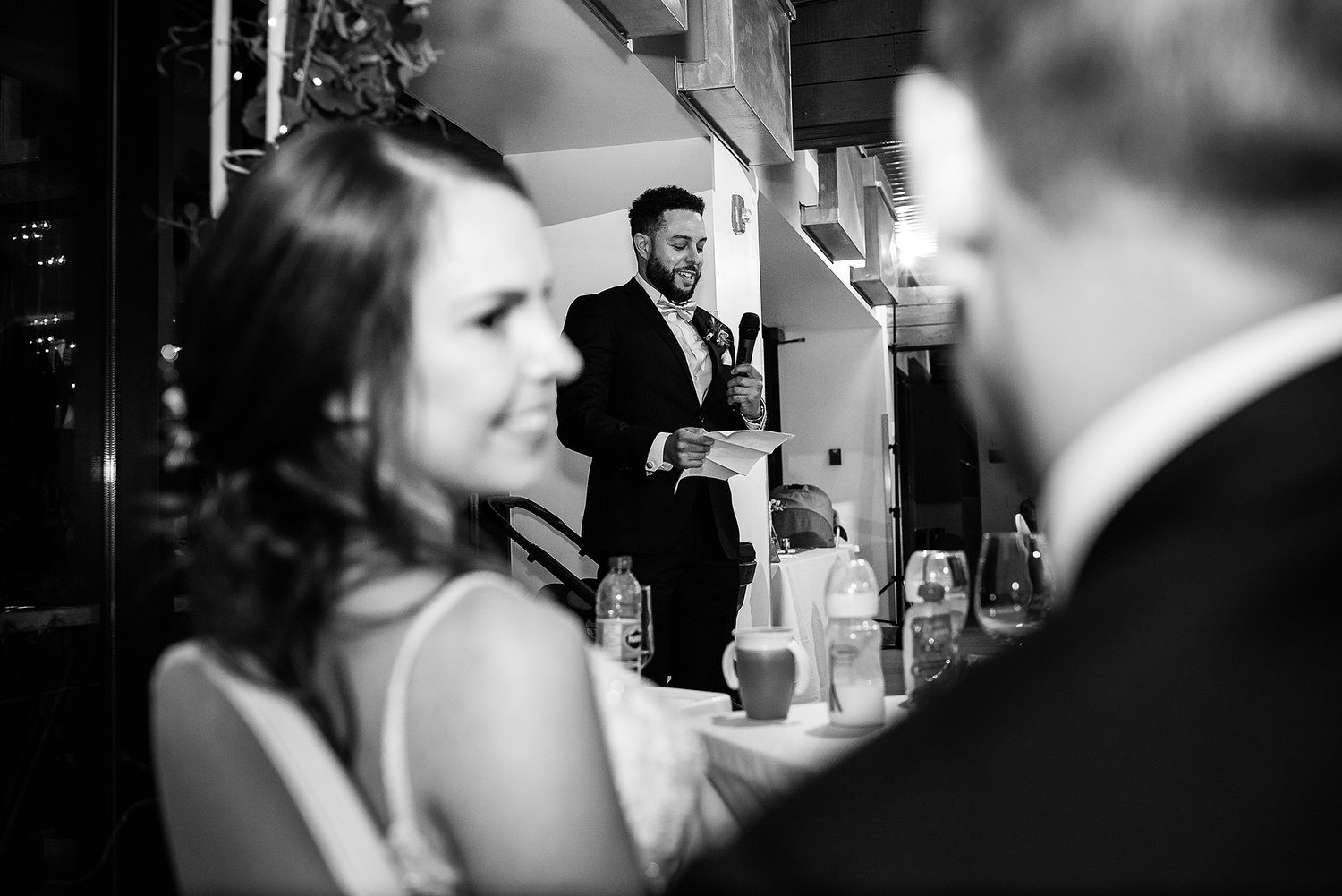 Black and white photo of guests socializing at an elegant bar during a wedding reception.