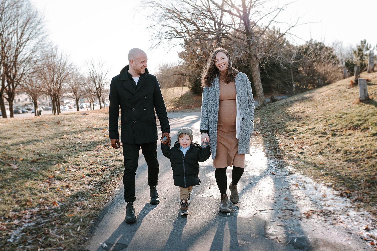 Family walking together on a snowy winter path during sunset.