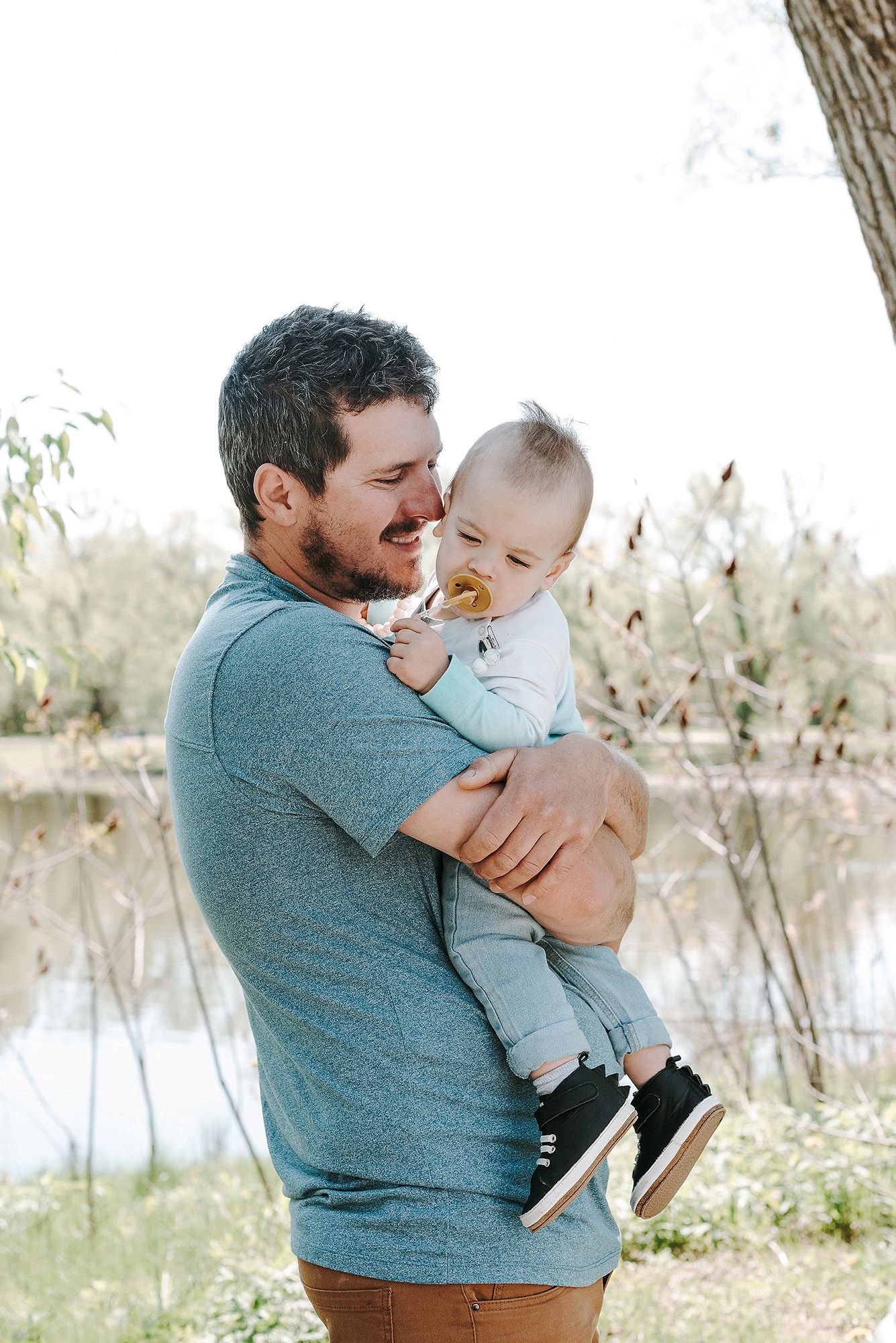 Tender family moments captured in natural light by a serene lakeside setting.