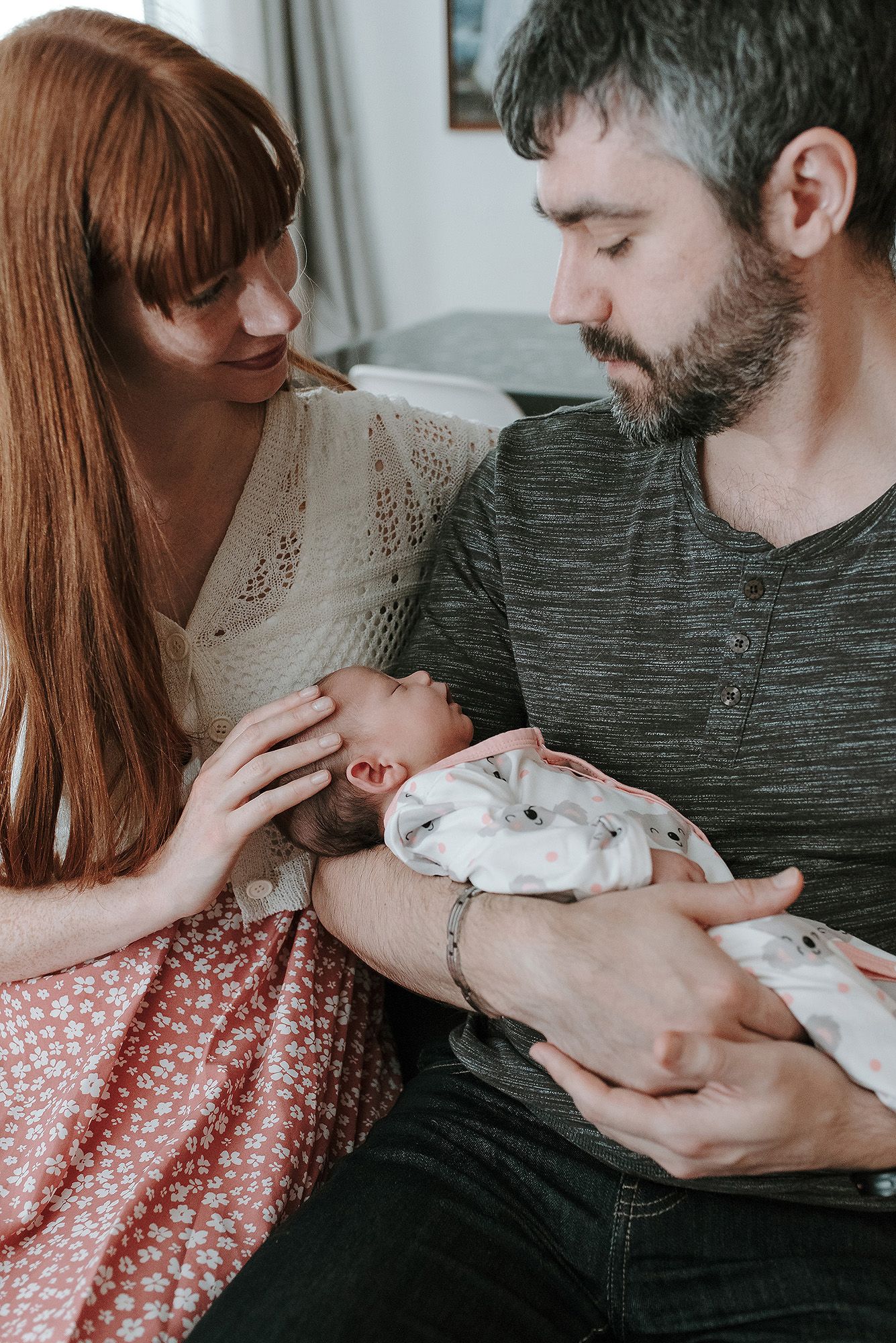 An intimate family moment as parents gaze lovingly at their newborn baby.