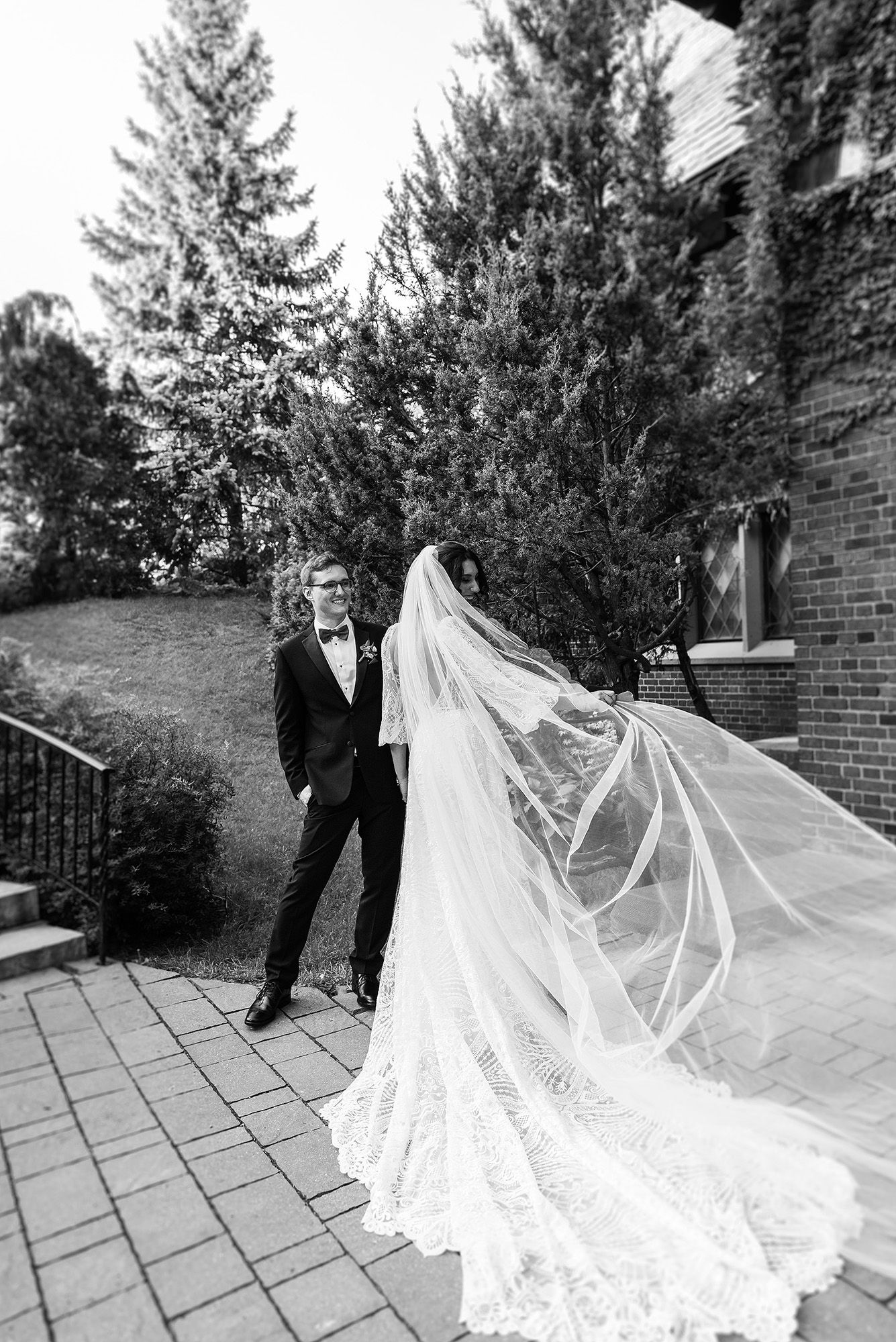 A romantic wedding photo series showing a flowing white veil billowing in the wind against an outdoor brick backdrop.