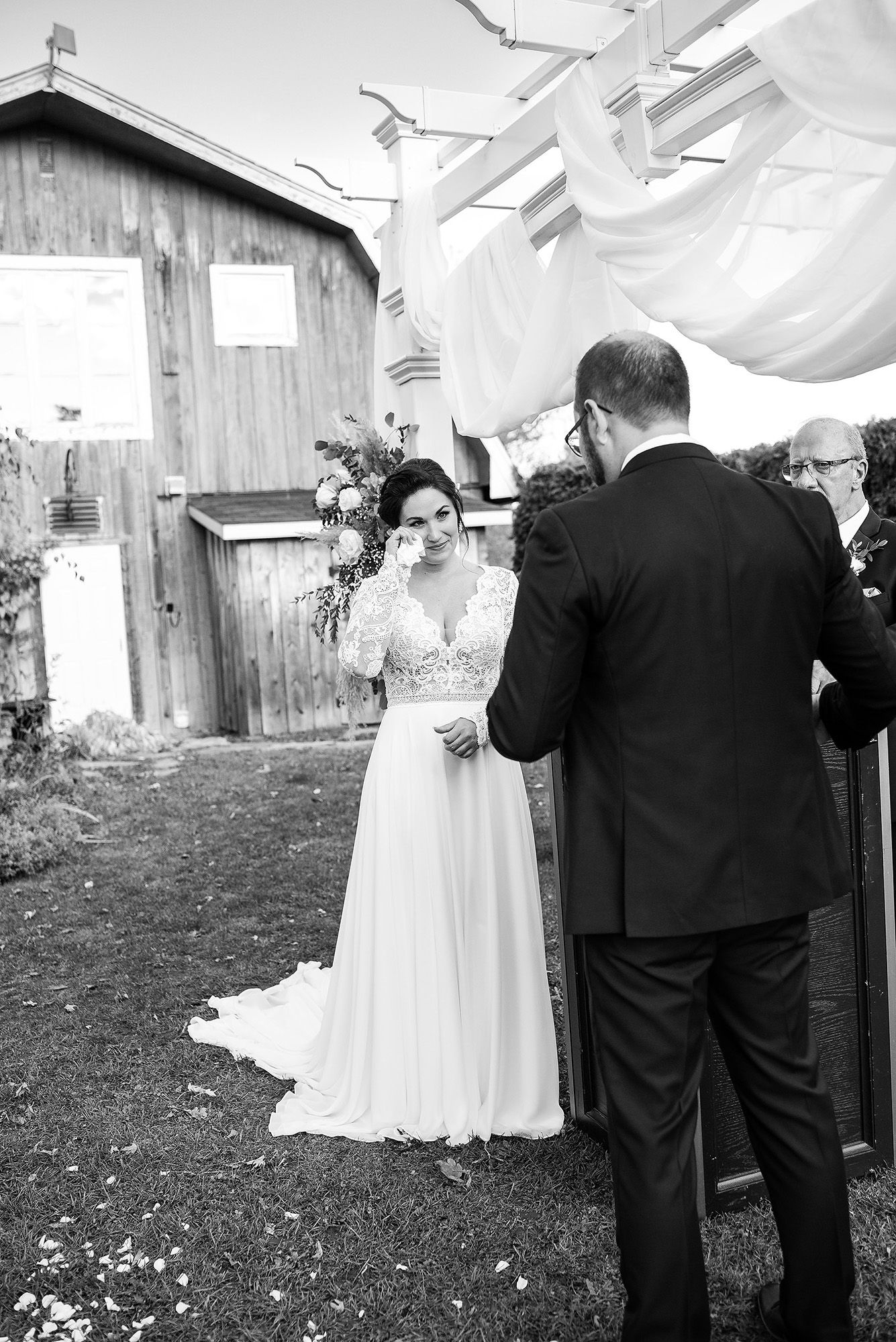A black and white photo series showing a tender first look moment between a bride in white and groom in dark suit outdoors.