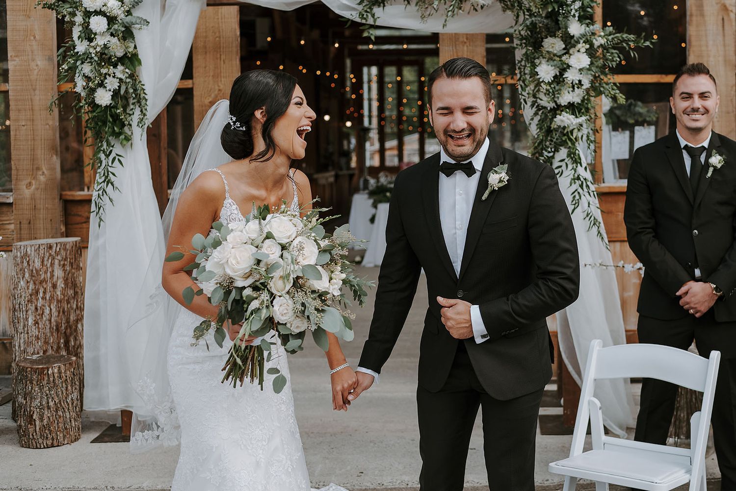 Wedding ceremony setup with rustic wooden beams and hanging floral decorations.