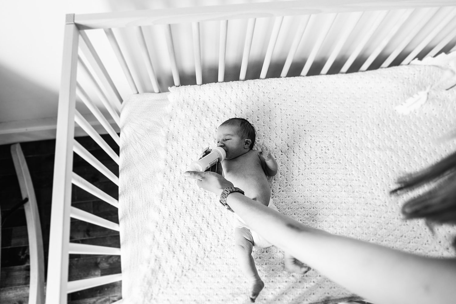 Artistic black and white shots of newborn baby details on white bedding.